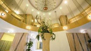 Un amplio atrio con una columna central, una lámpara decorativa y un gran arreglo floral.