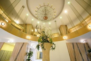 A spacious atrium with a central column, a decorative chandelier, and a large floral arrangement. - Gateway to Modern Elegance (Bucharest)