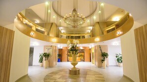 Un vestíbulo espacioso con una fuente central, un candelabro imponente y varios niveles con balcones.