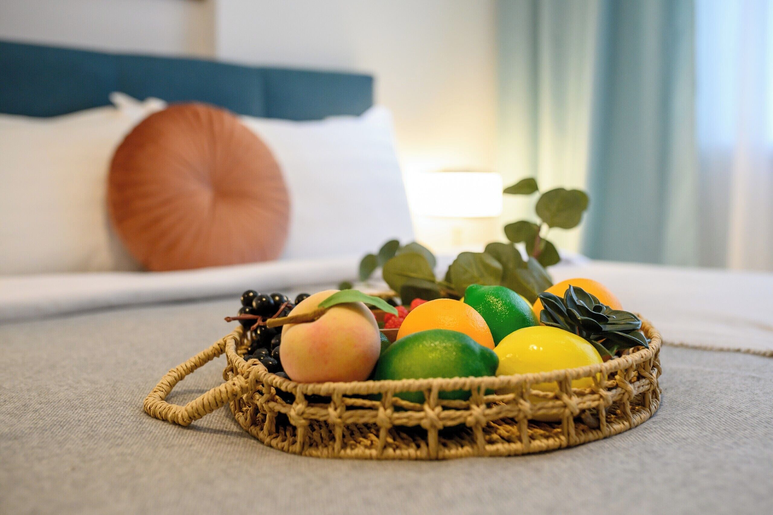 Una cesta de mimbre con frutas y una vela sobre la cama.