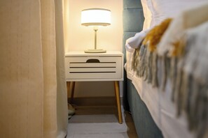 A bedroom with a bedside table, a lamp, a bed, and a curtain. - Gateway to Modern Elegance (Bucharest)