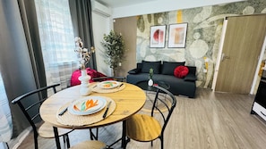 A dining area with a round table, chairs, and plates with leaf designs. - Modern Apartments in the Heart of the City (Bucharest)