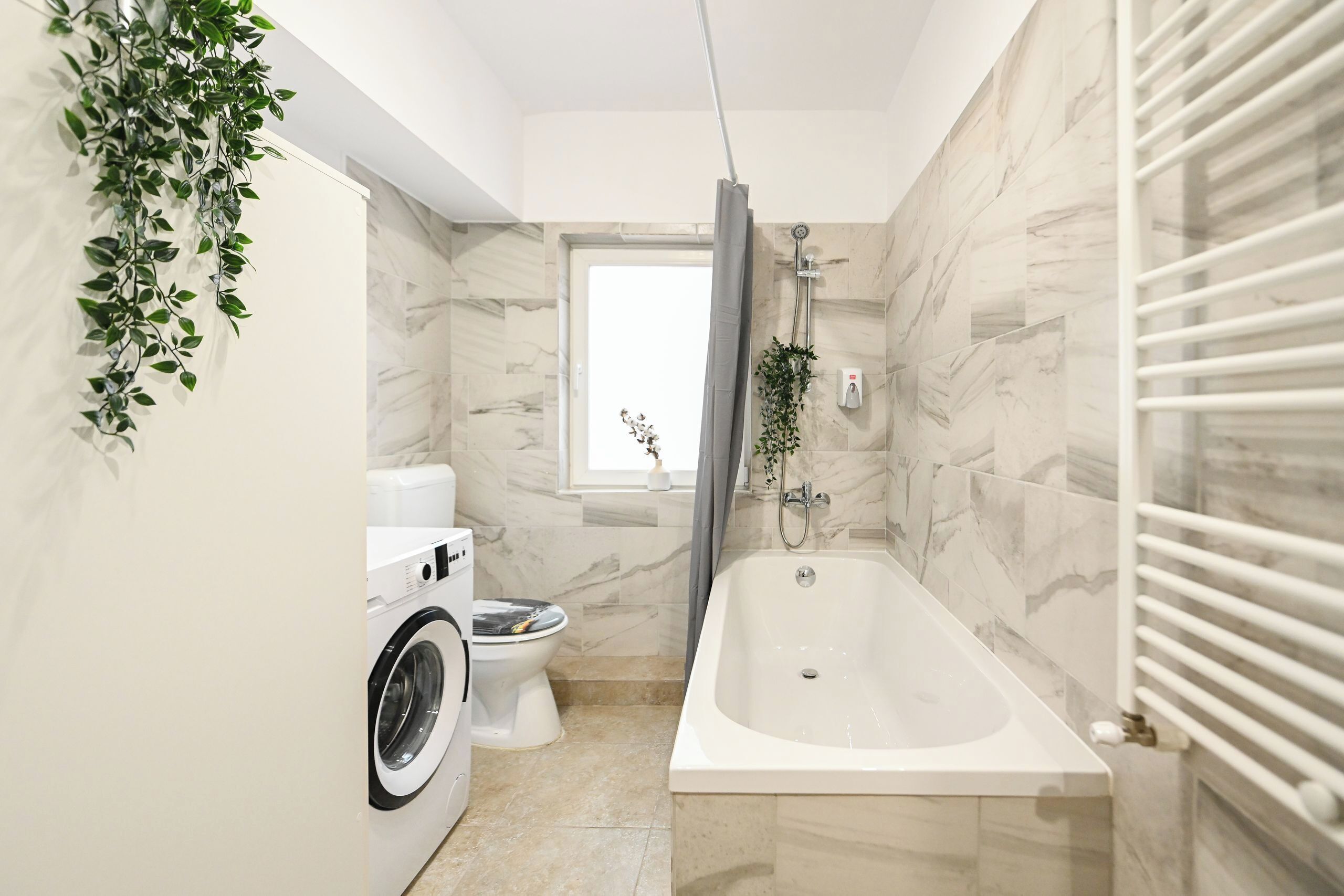 A bathroom with a washing machine, toilet, and bathtub.