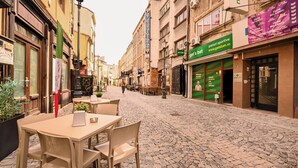 A cobblestone street with outdoor seating, a café, and various storefronts. - Modern Apartments in the Heart of the City (Bucharest)