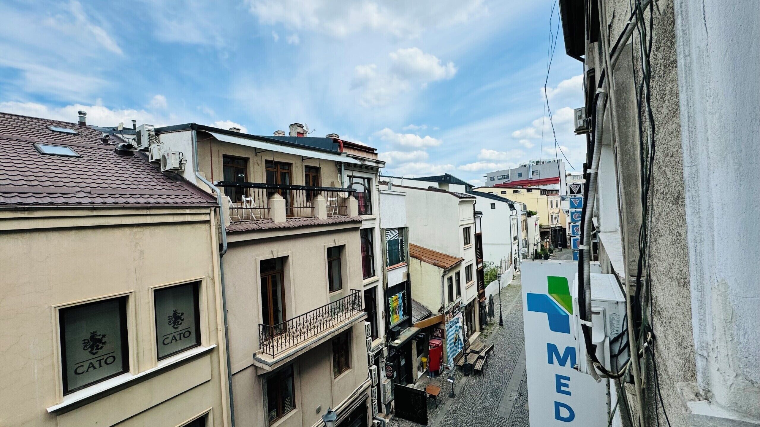 A narrow street with buildings, a visible CATO sign, and a MED sign.
