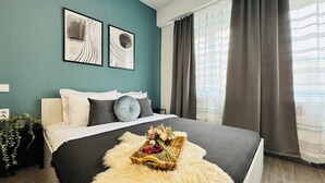 A bedroom with a bed, a bedside table with a plant, and two wall art pieces. - Modern Apartments in the Heart of the City (Bucharest)