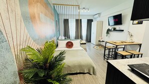 A modern hotel room with a bed, a dining area, a TV, and a large window with curtains. - Modern Apartments in the Heart of the City (Bucharest)