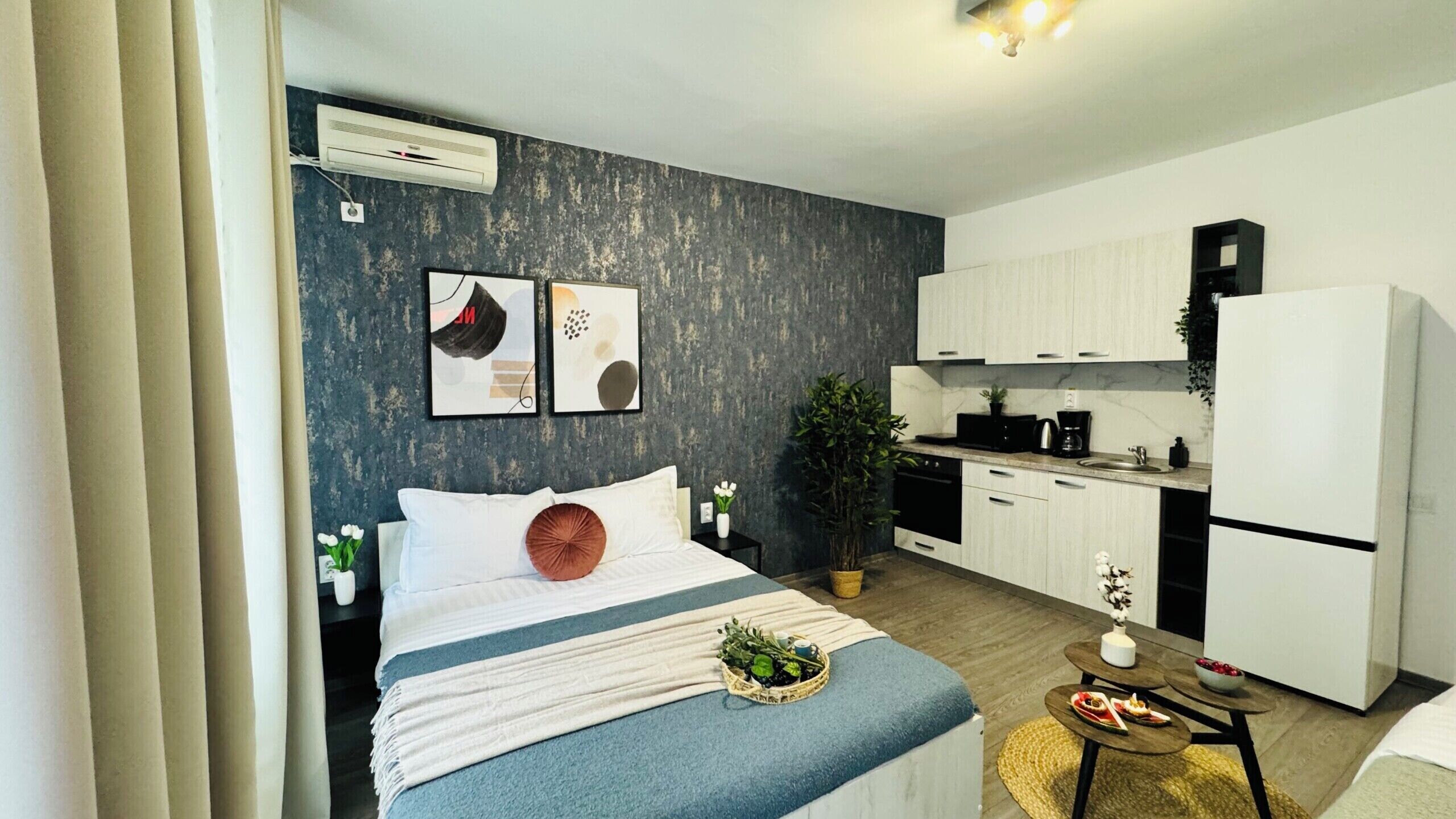 A modern bedroom with a bed, bedside tables, and a small sitting area with a table and chairs.