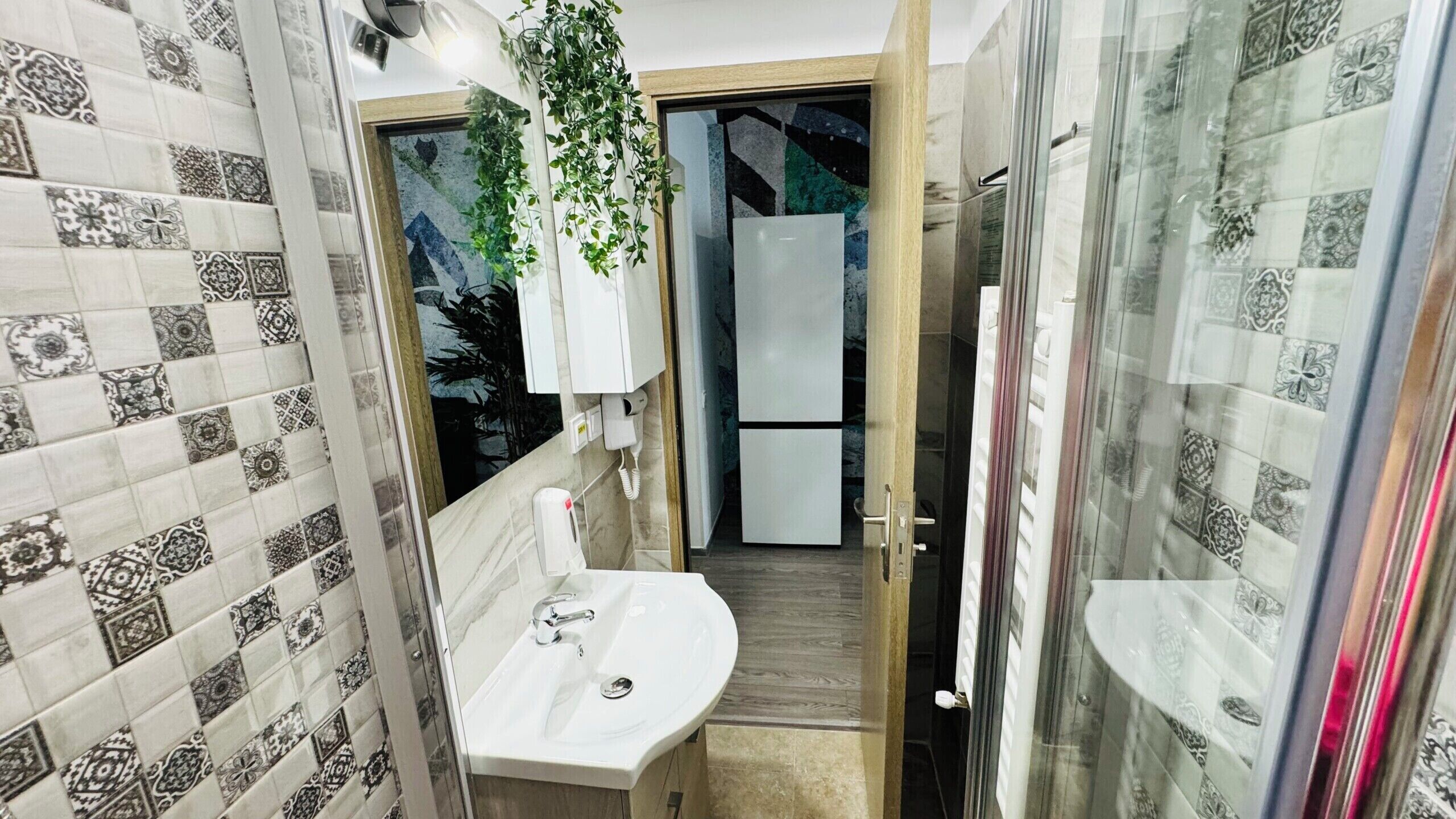 Un baño con lavamanos, espejo y azulejos estampados.