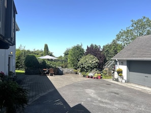 En boligkørsel med en belagt plads, en træstol og plantekasser.