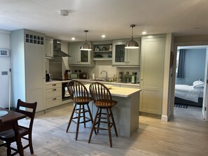 A modern kitchen with a dining area, wooden chairs, and a small island. - Ower Retreat Rosscahill (Rosscahill)