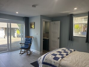 A bedroom with a bed, a rocking chair, a door, and a window. - Ower Retreat Rosscahill (Rosscahill)