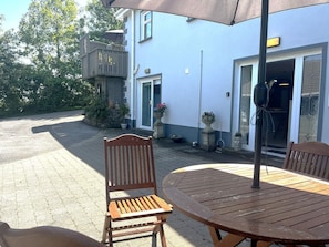 A wooden bench and table under a patio umbrella, with a house in the background. - Ower Retreat Rosscahill (Rosscahill)