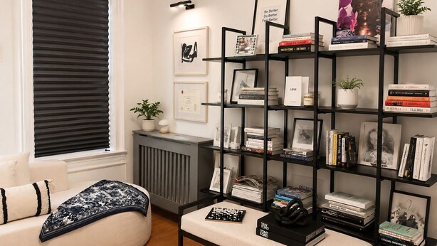 A living room with a black bookshelf, a white sofa, a radiator, and framed pictures on the wall. - FIFA World Cup Stay • Easy Transit to MetLife • Near NYC (Jersey City)