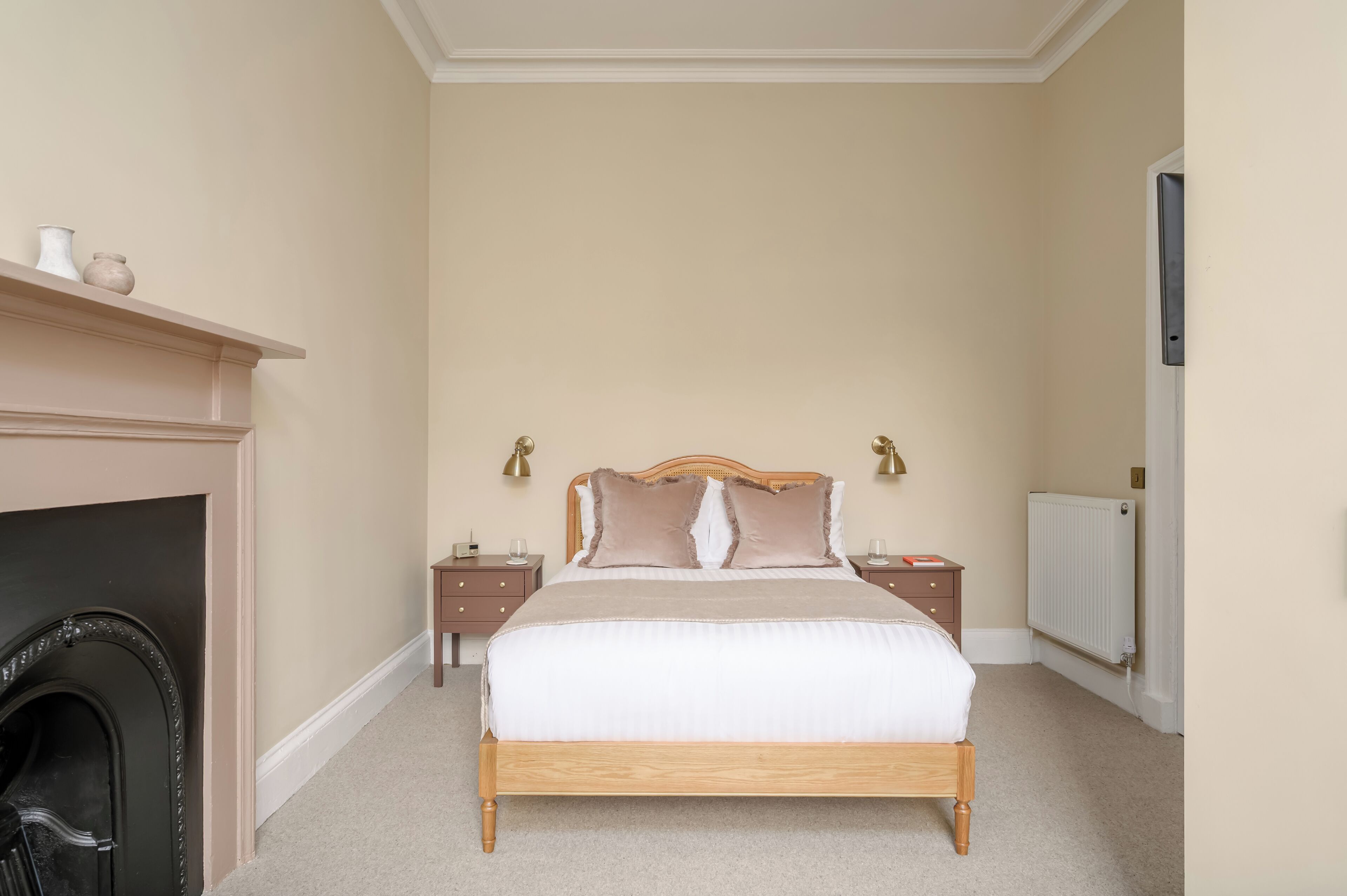 A bedroom with a bed, bedside tables, a fireplace, and a radiator.