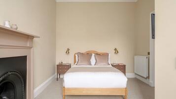 A bedroom with a bed, bedside tables, a fireplace, and a radiator.