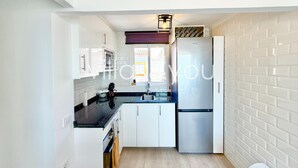 A modern kitchen with white cabinets, a stainless steel refrigerator, and a black countertop. - Torrevista La Mata Penthouse by Villas&You (Torrevieja)
