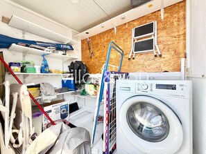 A laundry room with a washing machine, shelves with cleaning supplies, a ladder, and a window. - Torrevista La Mata Penthouse by Villas&You (Torrevieja)