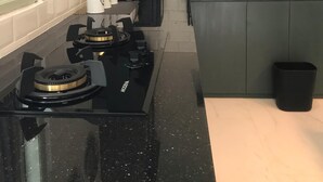 Een keuken met een gasfornuis, een koffiezetapparaat, een spoelbak en een klein eiland met een afvalbak.