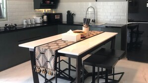 Een moderne keuken met een centraal eiland, hanglampen en een ingebouwde kookplaat.