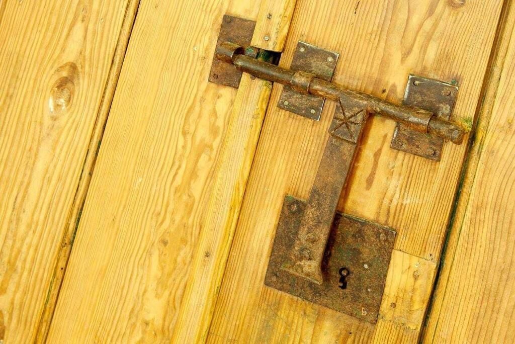 A wooden door with a metal latch and a keyhole.