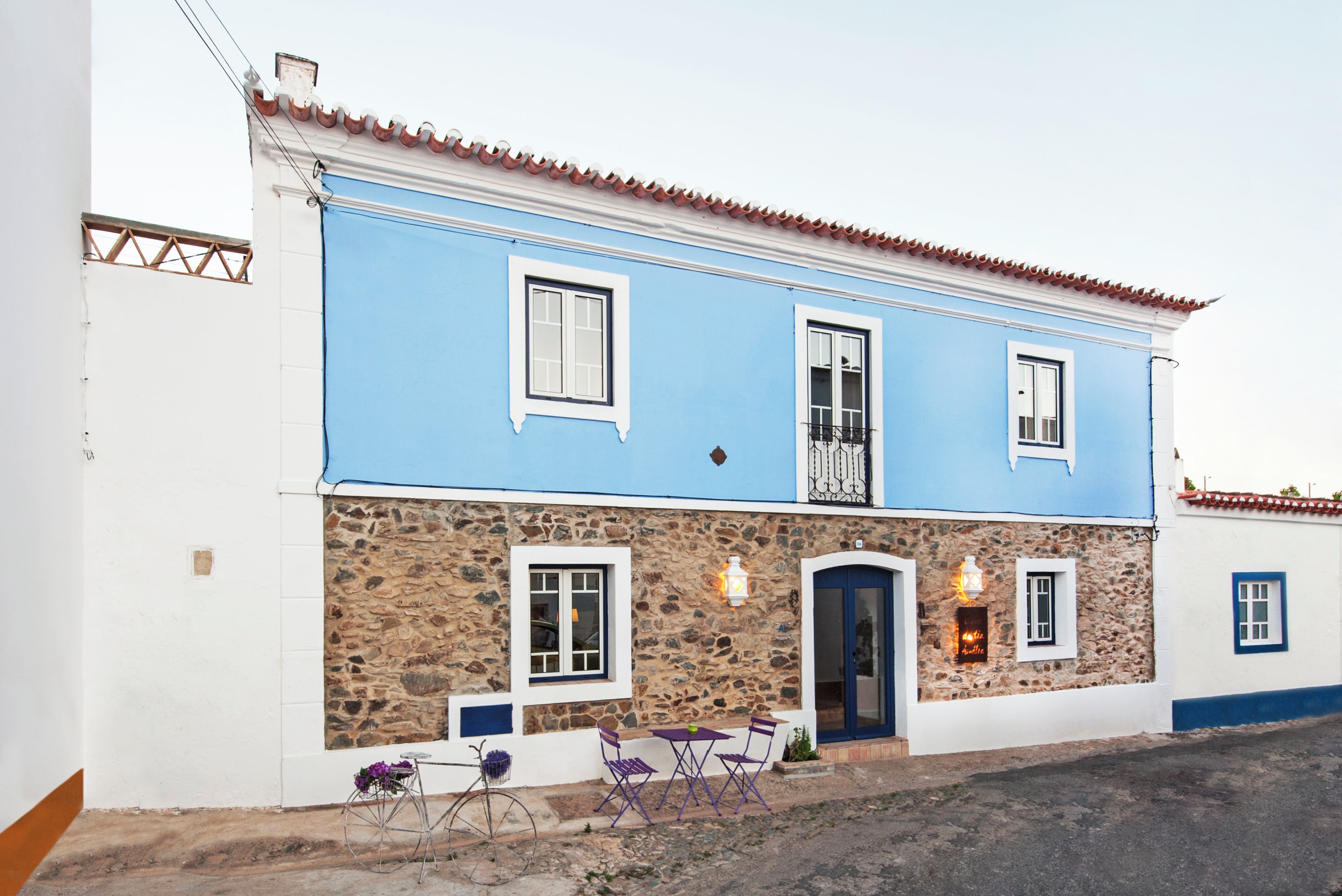 Un bâtiment à deux étages, doté d’une façade en pierre, d’une partie supérieure bleue et d’un toit recouvert de tuiles.