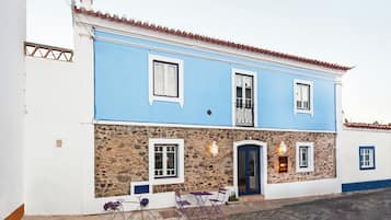 Un bâtiment à deux étages, doté d’une façade en pierre, d’une partie supérieure bleue et d’un toit recouvert de tuiles.