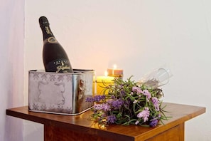 A bottle of champagne, a candle, and a bouquet of flowers on a wooden surface. - Casa da Tia Amália (Mértola)