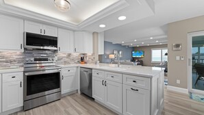 A modern kitchen with white cabinetry, stainless steel appliances, and a large island with a sink. - Sanibel Surfside 234: Beautifully Updated with Gulf Views! 2 PB Courts! (Sanibel)