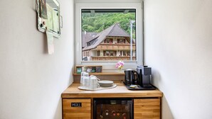 Una kitchenette pequeña con cafetera, escurreplatos y ventana con vista a un edificio tradicional.