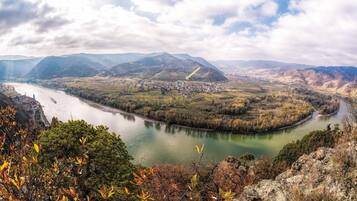 Um rio serpenteia por um vale, com uma cidade na margem e montanhas ao fundo.