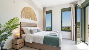 Une chambre à coucher avec un lit, une table de chevet, une lampe et une vue sur la mer.