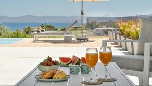Une table garnie de plats et de boissons, une vue sur la plage et une montagne en arrière-plan.