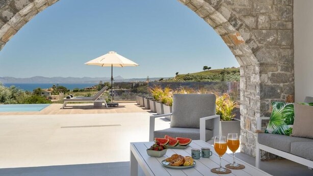 Un espace extérieur aménagé avec une arche en pierre, une piscine et une vue sur le paysage.