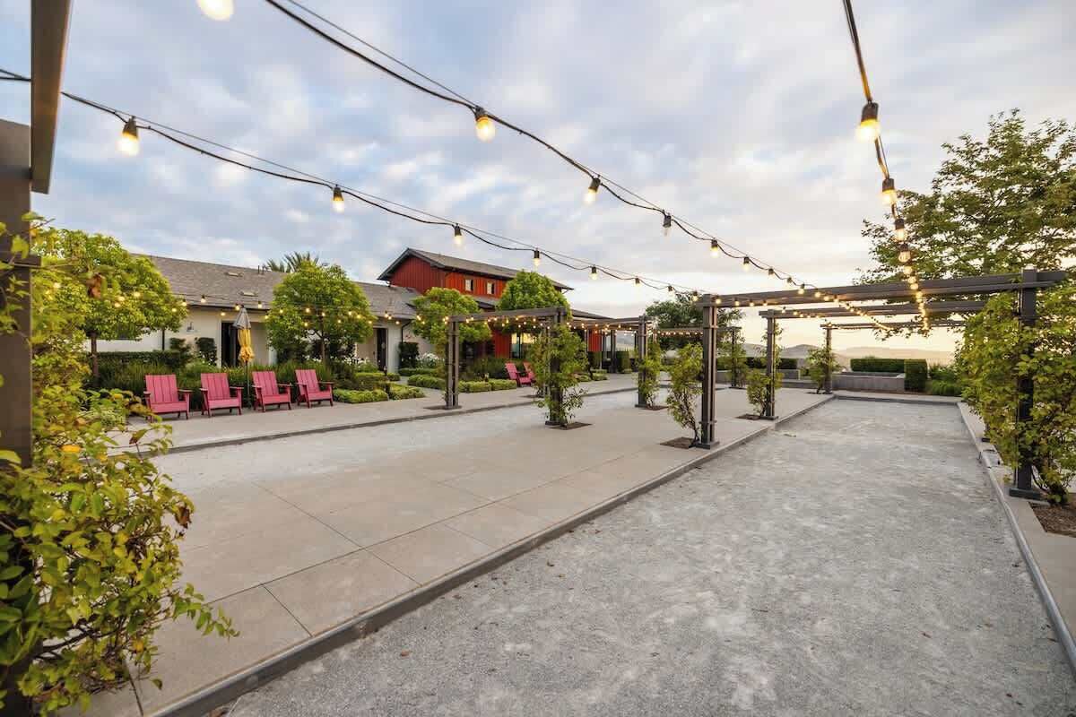 An outdoor patio area with string lights, red lounge chairs, and a building in the background.