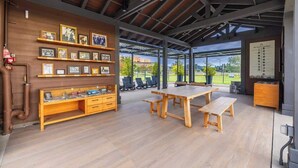 A spacious patio area with a wooden bench, a large table, and chairs. There are framed pictures on the wall and a fire extinguisher visible. - @ Marbella Lane - Designer Dream Oasis Family Home (San Juan Capistrano)