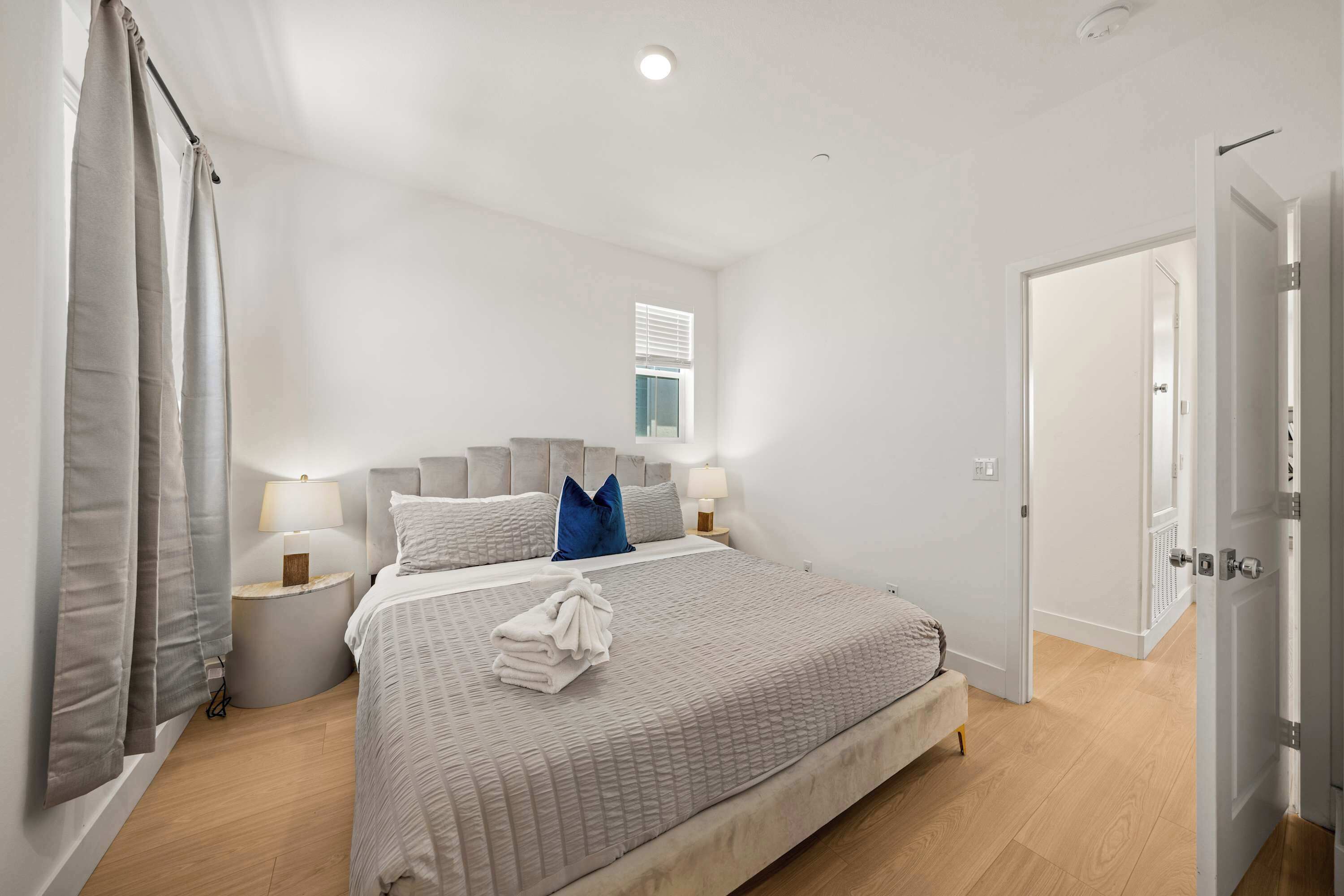 A bedroom with a bed, bedside tables, a window, and a door.