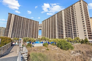 Ein Hochhaus-Hotel mit zahlreichen Balkonen, einem Poolbereich und einer Promenade.