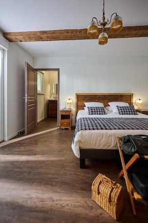 A bedroom with a wooden bed, a chandelier, a nightstand, and a wicker basket.. Le Clos de la Vieille Dame