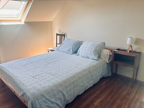 A bedroom with a bed, a nightstand, a lamp, and a window. - House of the Golden Reeds (Paulnay)