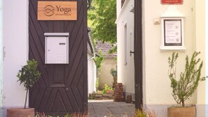 A building with a wooden door labeled 'Yoga,' a sign indicating 'Volksschule,' and a notice board with information. - Danube Atelier – The Garden Apartment (Rossatz-Arnsdorf)