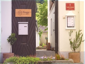 A building with a wooden door labeled 'Yoga' and a sign indicating 'Volksschule' with a plaque.
