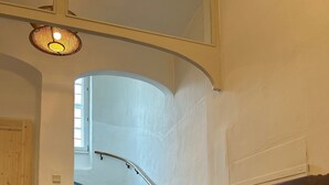 Uma escadaria com corrimão, uma cadeira de madeira, um vaso de planta e um tapete texturizado.
