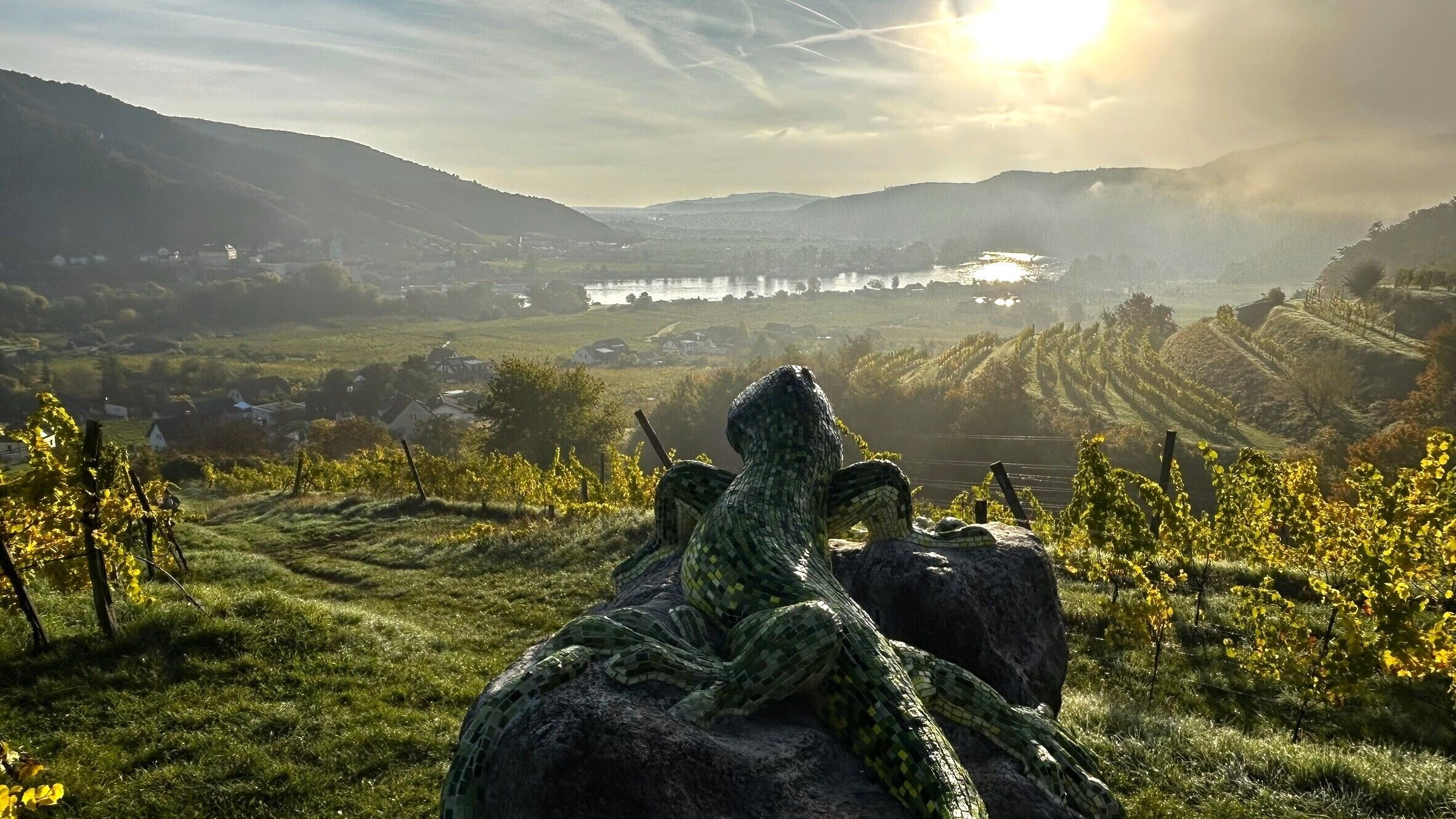 Paisaje de viñedo con una roca grande y una escultura de serpiente.