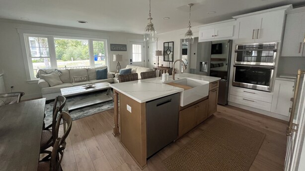 Een moderne keuken met een centraal eiland, inbouwapparatuur en een zithoek met een bank en tafel.