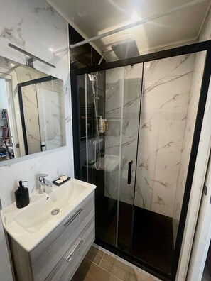 A modern bathroom with a marble vanity, a glass-enclosed shower, and a large mirror. - Apartment in the center of Nice (Nice)
