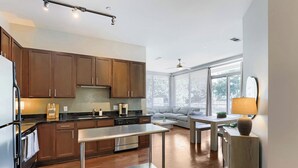 Eine moderne Küche mit Holzausstattung, einem Edelstahlkühlschrank und einem Essbereich mit Tisch und Stühlen.