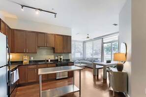 Eine moderne Küche mit Holzausstattung, einem Edelstahlkühlschrank und einem Essbereich mit Tisch und Stühlen.