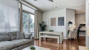 Ein Wohnzimmer mit einer Couch, einem Couchtisch, einem Esstisch und einem Deckenventilator.