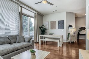 Ein Wohnzimmer mit einer Couch, einem Couchtisch, einem Esstisch und einem Deckenventilator.